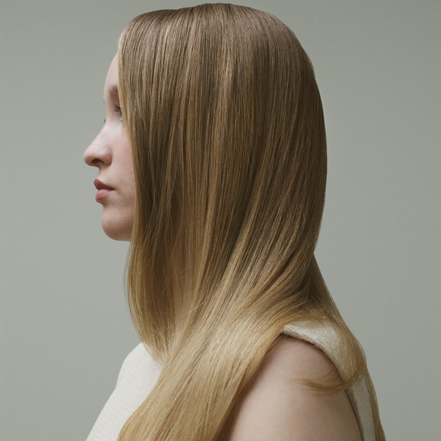 Model in profile with straight blonde hair in the Honey Glaze shade